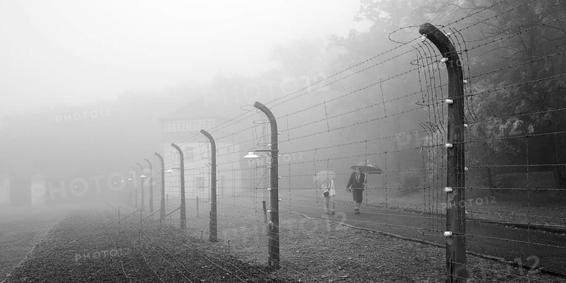 Reconstructed camp fence with people in the fog at beech forest concentration camp, now a concentration camp memorial, Weimar, Thuringia, Germany