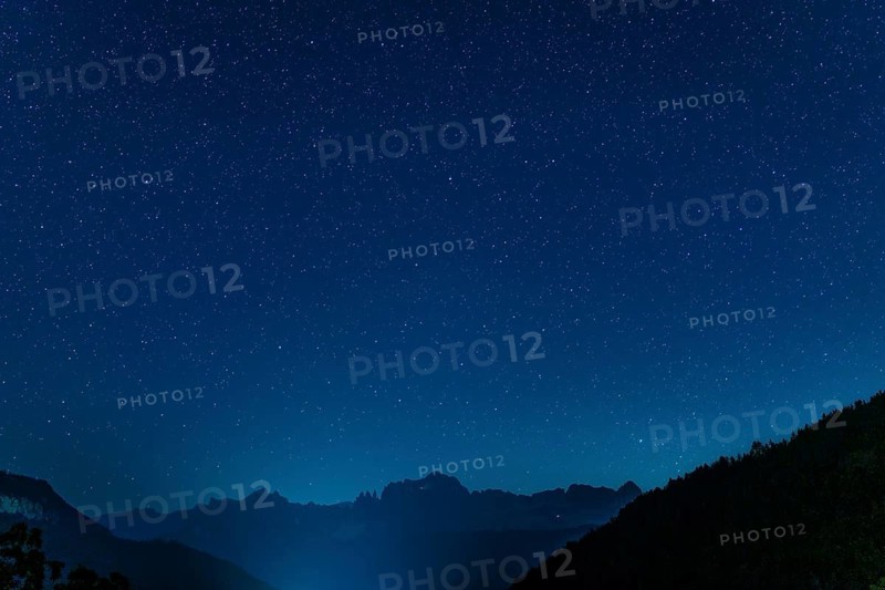 Breathtaking view of a majestic night sky filled with twinkling stars illuminating a dark mountain range, creating a serene and awe-inspiring landscape