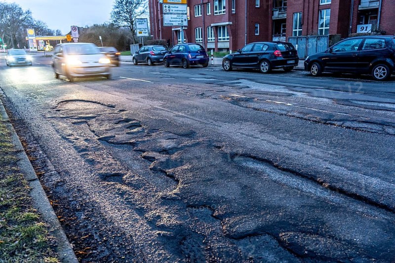 Many large potholes on an inner-city road, Lange Straße in Krefeld-Uerdingen, the heavily frequented road consists of more potholes than intact asphalt, road damage, vehicles can barely avoid, North Rhine-Westphalia, Germany