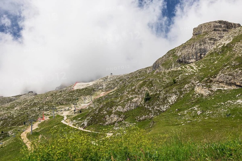 Clouds and mist partially obscure distant mountains creating a serene atmosphere in Dolomites, Italy.