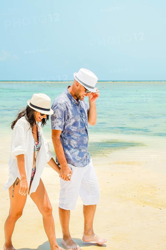 Happy caucasian couple enjoy walk on tropical holiday vacation together having fun on sunny beach. Trip get away promo ad postcard paradise background.Zanzibar