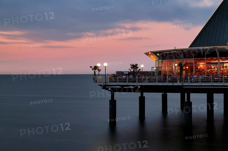 Illuminated restaurant terrace with tourists, Heringsdorf pier at dusk, long exposure, Baltic resort Heringsdorf, Usedom, Mecklenburg-Western Pomerania, Germany