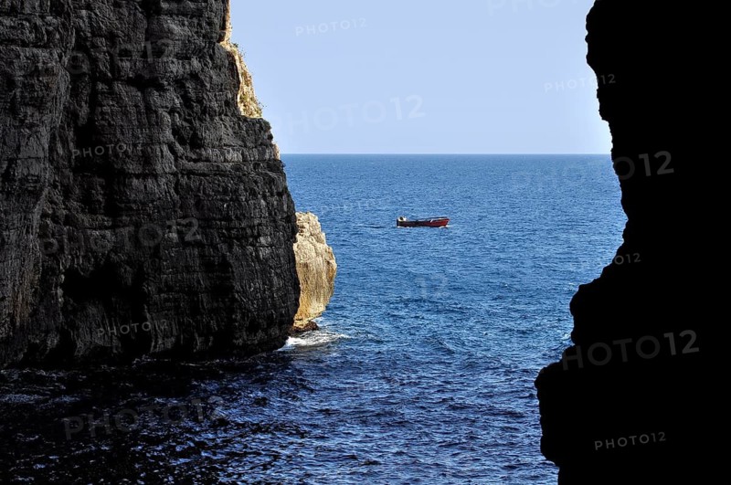 Karst cave Grotta del Turco, Cave of the Turk, Montagna Spaccata, split mountain, Gaeta, Tyrrhenian Sea with fishing boat, Latina, Lazio, Italy