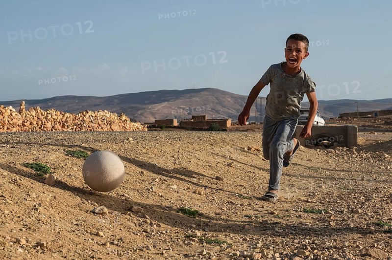 Taouloukoult, MOROCCO - OCTOBER 6, 2024: young boys spend the afternoon playing amateur football on a stone pitch