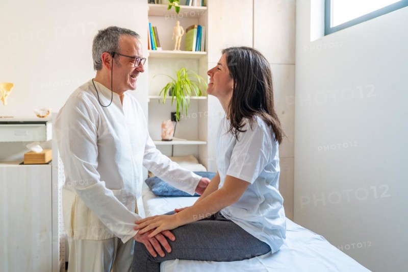 Mature Qi gong expertise masseur talking to a patient in a clinic