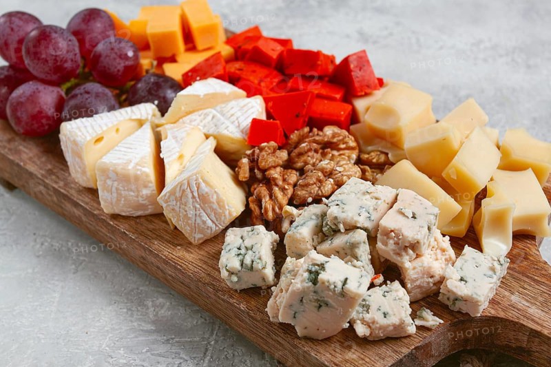 Assorted cheese on a wooden board, with grapes and walnuts, appetizer, no people
