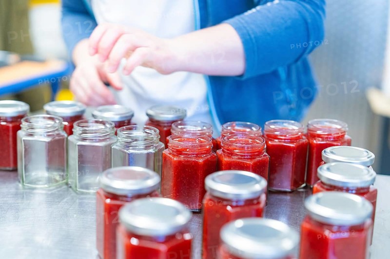 Person working with jars, some are unfilled, others are filled with red jam, jam production, Haselstaller Hof, Wildberg Gültlingen, district of Calw, Black Forest, Germany