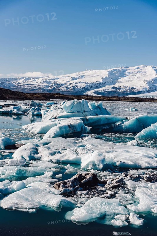 A stunning scene of icebergs floating in the calm waters of the Jokulsarlon glacier in Iceland. Snow-capped peaks and clear skies complete this tranquil landscape