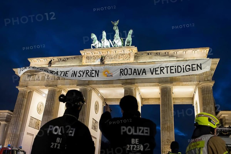 Police officers from the High Altitude Rescue Team remove a banner with the inscription For Democracy in Syria / Defend Rojava from the Brandenburg Gate, Berlin, 16 December 2024