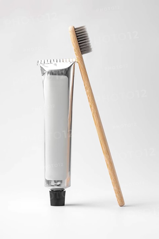 Eco-friendly bamboo toothbrush alongside a sleek toothpaste tube, set against a minimalist white background. Ideal for sustainable and zero waste living enthusiasts
