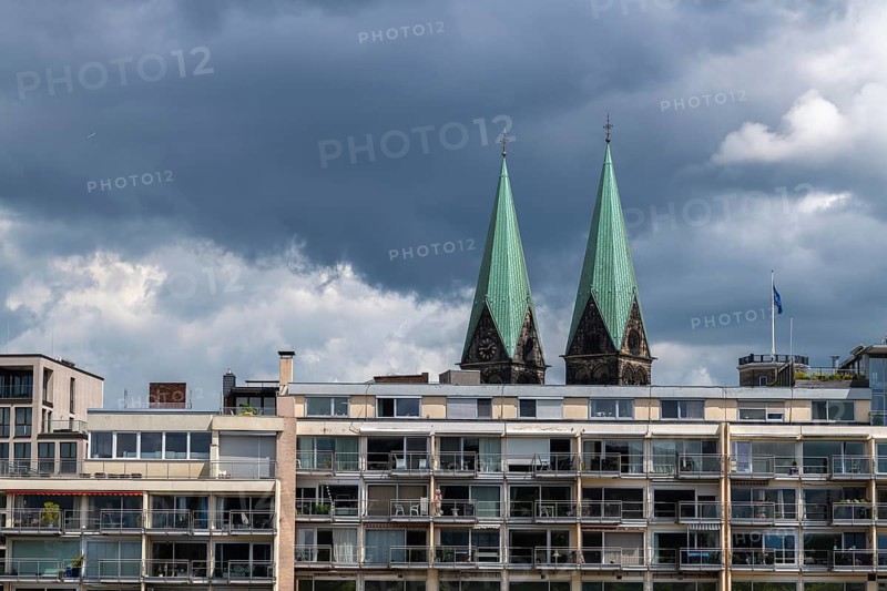 Apartments on the Weser promenade in front of the towers of Bremen Cathedral, Hanseatic City of Bremen, city-state, apartment building, apartment building, condominiums, residential complex, façade, balconies, terrace, living comfort, modern architecture, living space, city apartment, penthouse, window front, quality of living, old town, Hanseatic League, historic waterfront, cityscape, city history, tourism, tourist attraction, city life, culture, balconies, dark cloudy sky, rain clouds, sunshine, northern Germany, Germany
