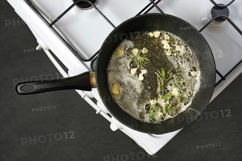 Infusing olive oil and melted butter with the flavour of fresh garlic and rosemary in a skillet