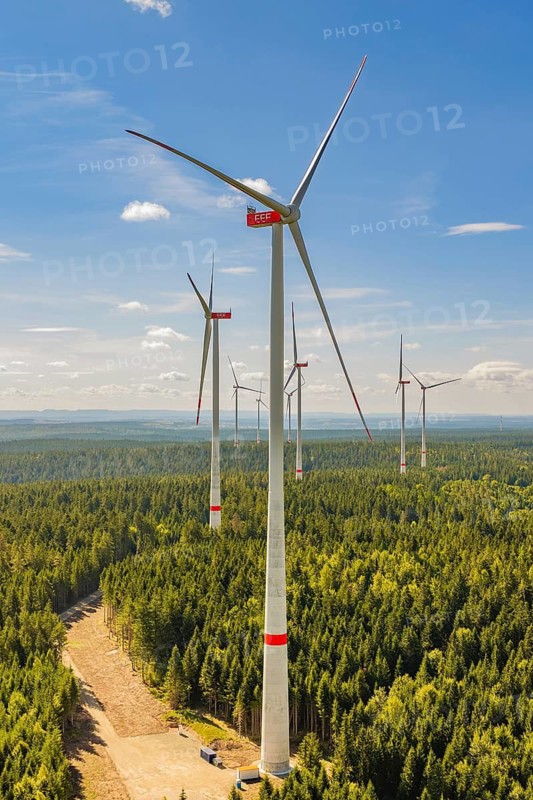 Tall wind turbines rise above a thick forest under a clear blue sky, Besenfeld, Freudenstadt district, Germany