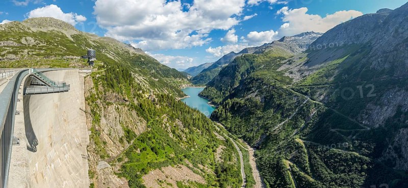 View from air side of Kölnbrein dam facing away from the water to the left free-floating viewing platform Airwalk casts shadow on dam, Galgenbichl Reservoir in the background, hiking trail from dam to Malta Valley, Carinthia, Austria