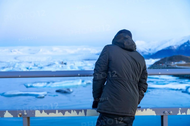 An adventurous young man on the bridge looking at Jokulsarlon lake in winter in Iceland