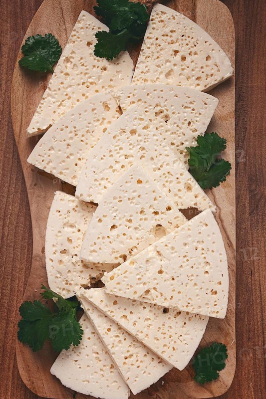 Sliced Georgian cheese, factory grade, on a wooden board, top view
