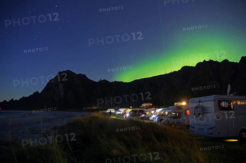 Motorhomes park on the beach under a clear night sky with northern lights and dark mountains, campground, Laser, Andøya Space, Bleik, Vesteralen, Norway