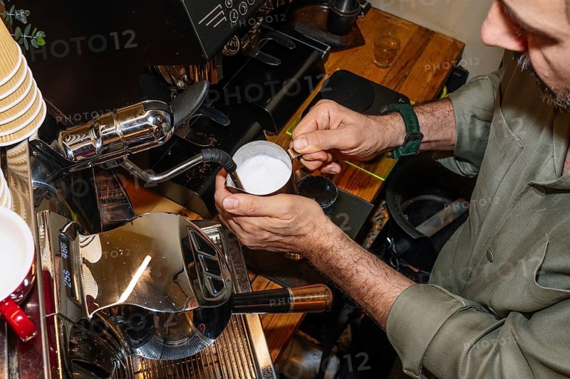 A barista froths milk for a specialty coffee using a professional espresso machine. This process highlights the skill and precision needed in crafting a perfect cup