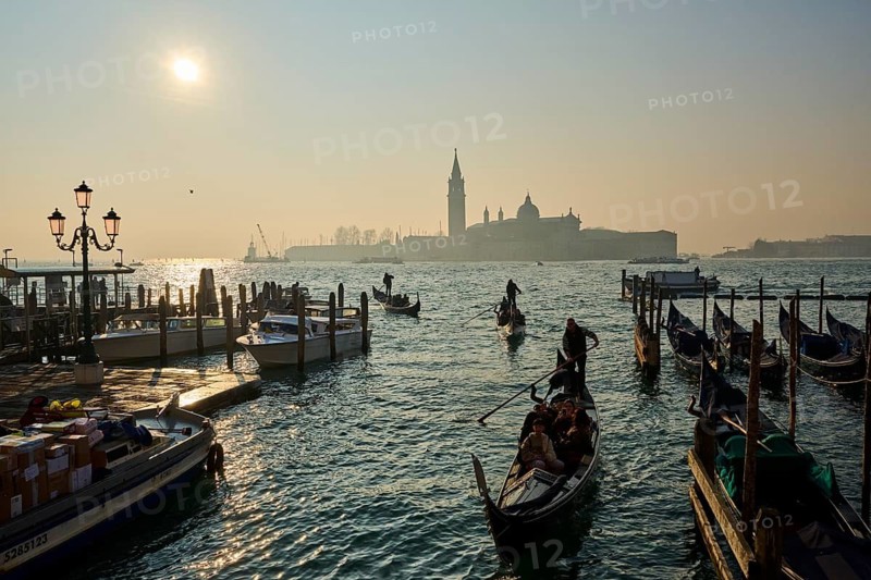 View from 'Ponte della Paglia' bridge on church 'Giorgio Maggiore' with gondolier in front on a foggy morning at sunrise in Venice in winter, Italy