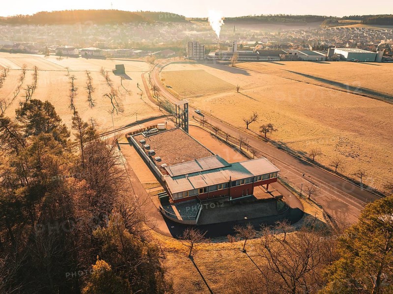 Building with surrounding fields and forest in golden morning light, Althengstett fire station, Calw district, Germany