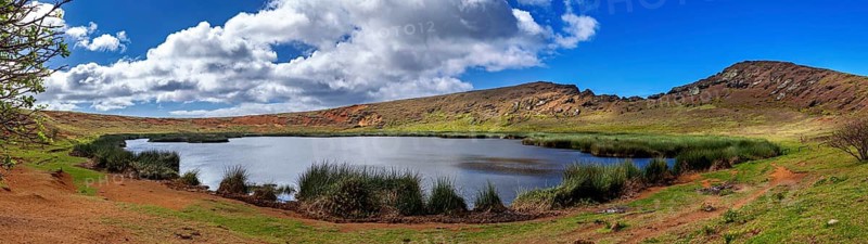 Panorama of a tranquil lake surrounded by hills and clouds in the blue sky, The landscape of Easter Island in the Pacific Ocean