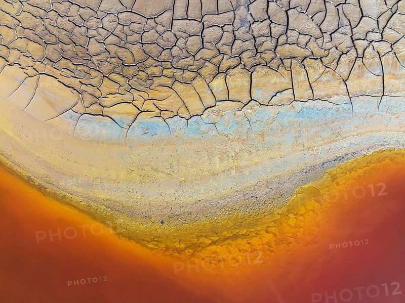 Cracked earth at the bank of the Rio Tinto (Red river) with its deep reddish hue due to oxidised iron minerals in its water, aerial view, drone shot, Huelva province, Andalusia, Spain