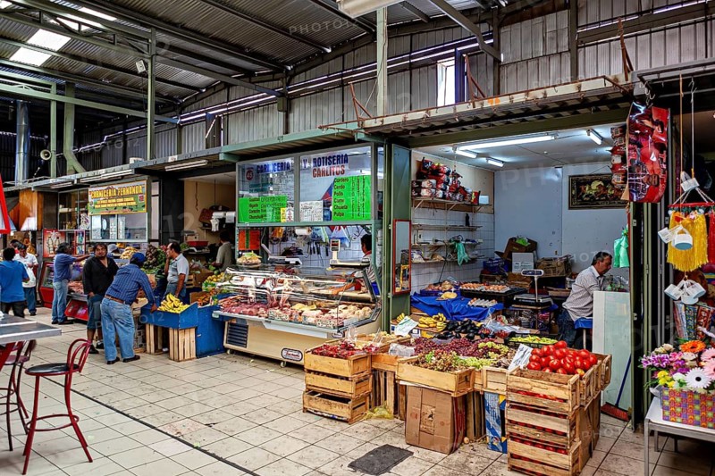 Covered market area with boxes full of fruit and meat products, bustling atmosphere, The Calama market hall in Chile