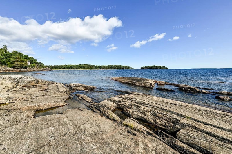 Clear sky over rocky archipelago coastline with granite archipelago with green forest and blue water at Lake Vänern, Värmlandsnäs peninsula, Värmlands län, Sweden