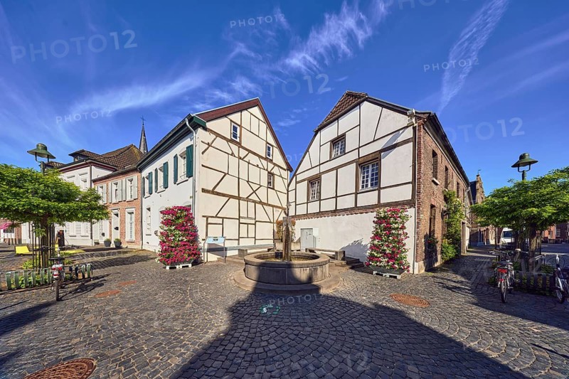 Old town, historic town center, historic half-timbered houses, houses, fountains, lantern, street, paving stones, city trees, flower pots, blue sky, cirrus clouds, intersection of Weinstraße, Feldstraße and Mühlenstraße, Wachtendonk, Kleve district, North Rhine-Westphalia, Germany