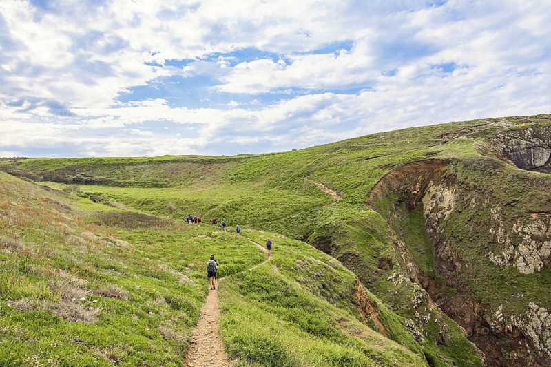 People hiking on a path in a beautiful coastal area at a rolling landscape in the summer, Crozon peninsula, Bretagne, France