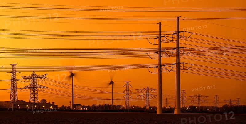 High-voltage electricity pylons, transmission towers and wind turbines at sunset near the Borssele Nuclear Power Station, Zeeland, Netherlands