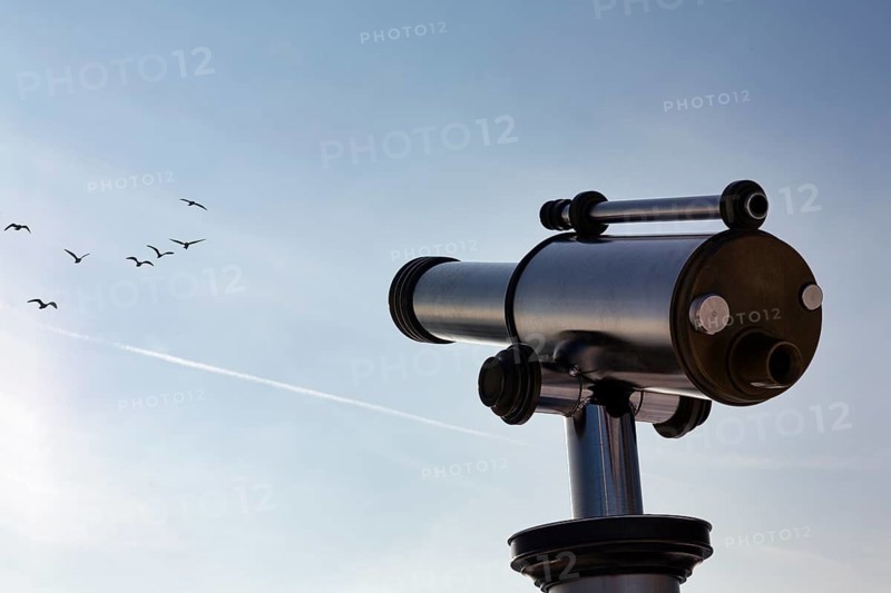 Telescope pointing to blue sky with flock of birds, symbolic image hobby birdwatching, nature observation
