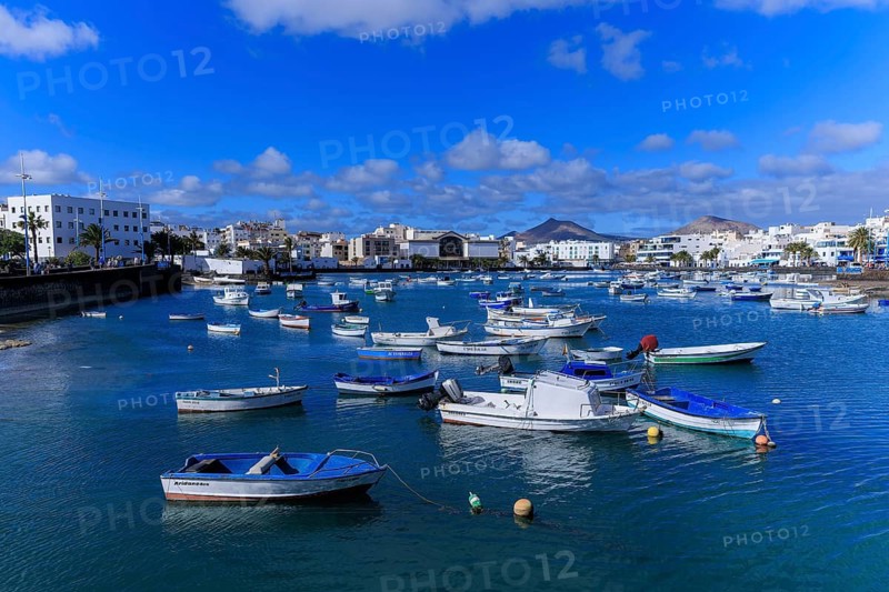 Lanzarote, Canary Islands, Spain, Europe, Charco San Gines harbour area in Arrecife, boats swim in a quiet harbor in front of a coastal town with mountains in the background
