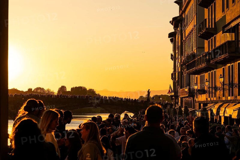 Crowd at sunset on the river Arno, light-filled evening mood, back light, old town, Florence, Tuscany, Italy