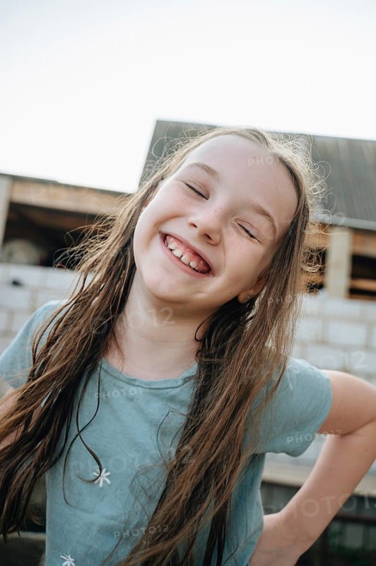A happy girl with a big smile plays and enjoys herself at an unfinished construction site, surrounded by building materials and a partially completed structure