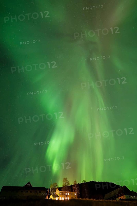 Intense northern lights (aurora borealis) over an illuminated house, Alvdal, Hedmark, Innlandet, Norway, October 2025