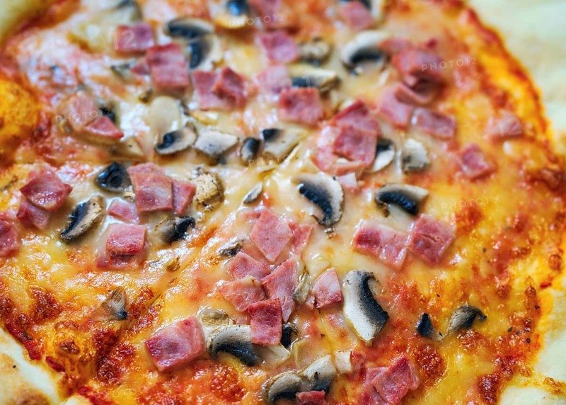 A delicious pizza topped with savory ham, mushrooms, and gooey cheese on a golden crust. Perfectly baked to showcase its vibrant colors and mouthwatering ingredients