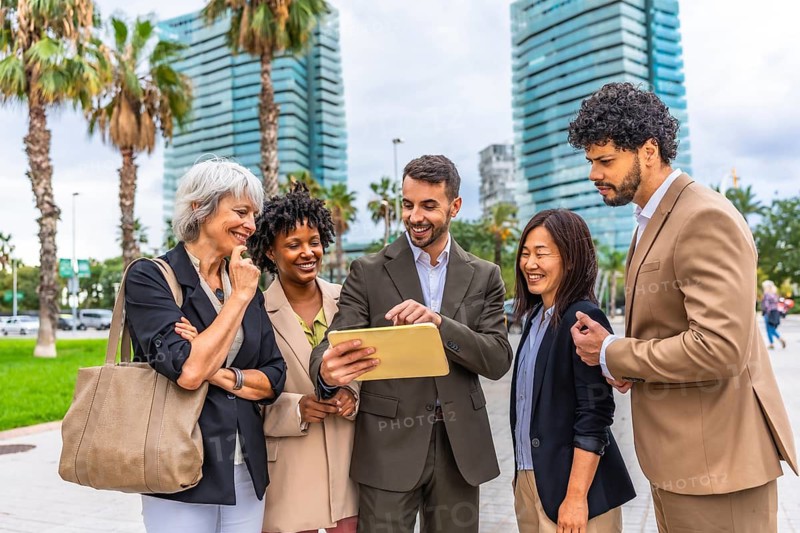 Manager using digital tablet while talking with business people standing in an outdoor meeting