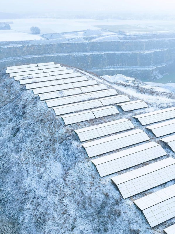 Solar panels on a snow-covered hill in a wintry landscape and fog, Nagold, Black Forest, Germany