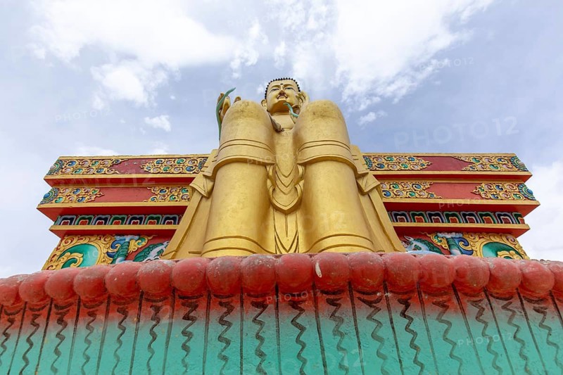 Stunning low angle view of a golden Buddha statue against a vibrant sky, located in the serene Zanskar Valley of Ladakh, India, showcasing intricate artistry and vibrant colors