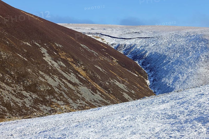 Gully and snow covered northside and sunlit southside of hills in the Strathdearn valley in winter, Scottish Highlands, Scotland, UK