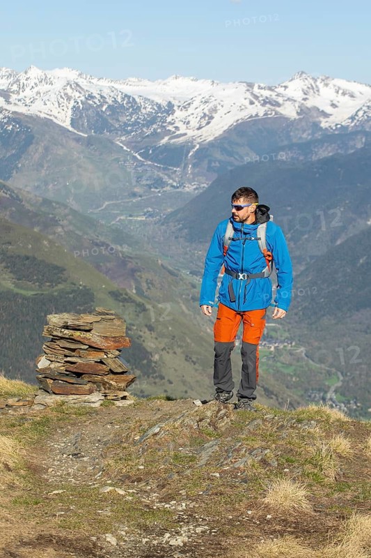 A man enjoys a trekking adventure in the stunning Pyrenees mountains, clad in vibrant outdoor gear. The breathtaking landscape highlights the rugged natural beauty