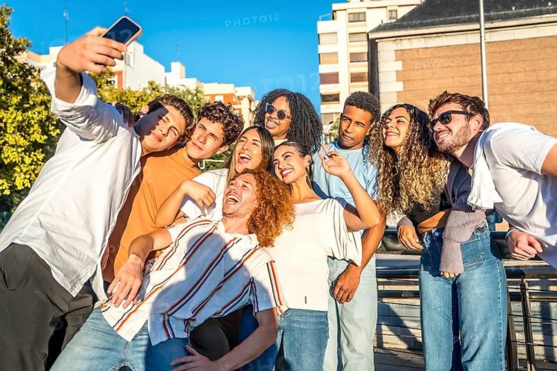Smiling diverse young friends enjoying a day at city taking selfie together