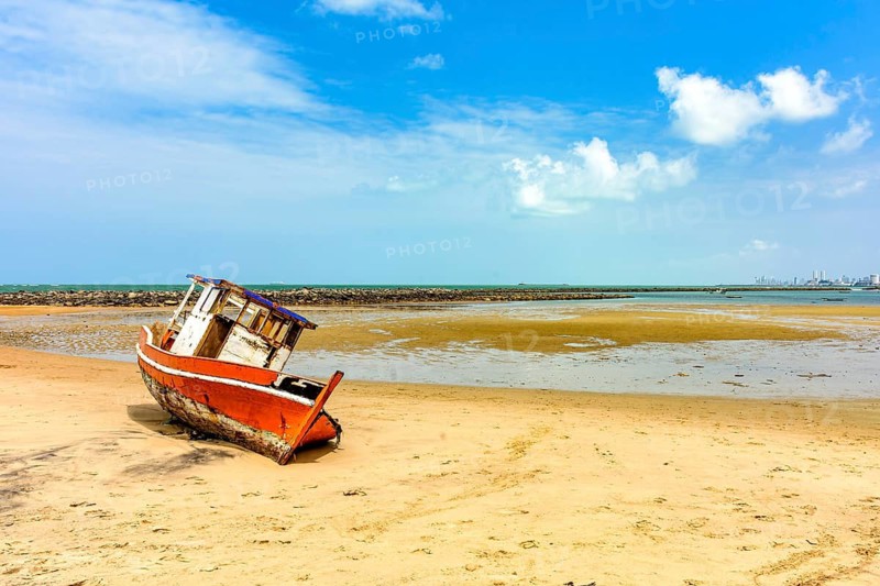 Abandoned and deteriorated fishing trawler stranded on the beach sand in Olinda, Pernambuco