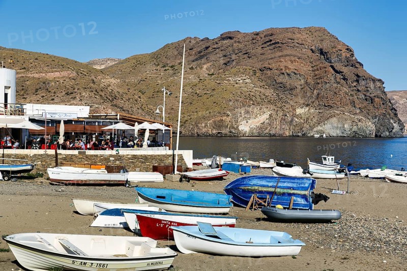 Playa de las Negras, numerous small fishing boats, distinctive Cerro Negro, mountain of dark volcanic rock, waterfront with bars and restaurants, typical, quiet fishing village, coastline, Cabo de Gata-Nijar nature park Park, Las Negras, Nijar, Almeria, Andalusia, Spain