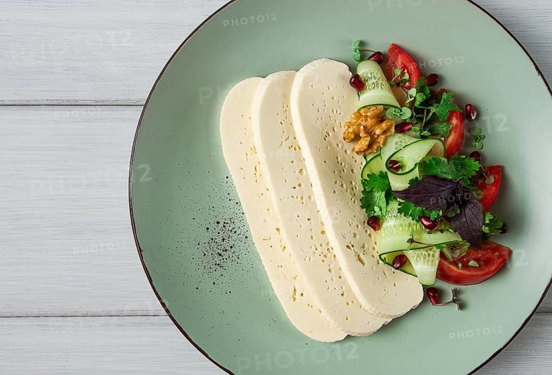 Sliced Imeruli cheese, Georgian cheese, with vegetables, top view, no people
