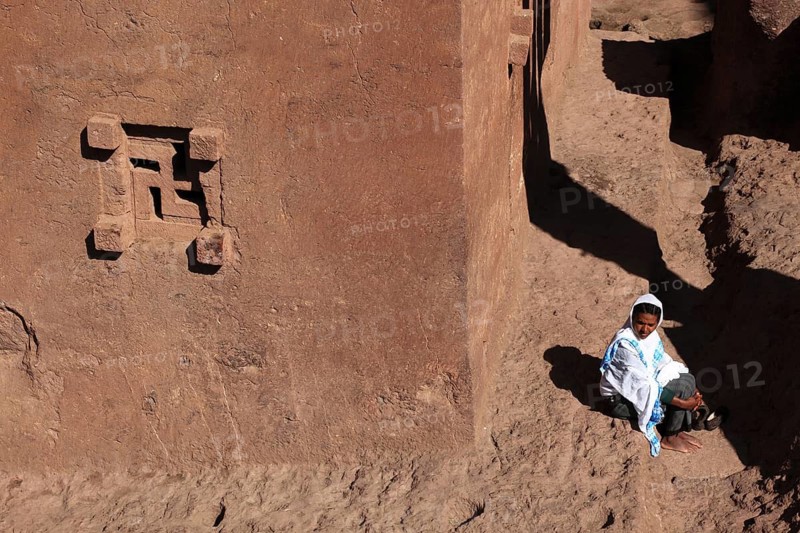 Rock churches of Lalibela, woman, pilgrim sitting in front of the Bete Golgata, Golgotha Church, Ethiopia