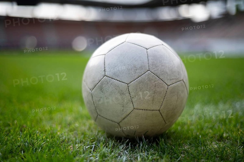 White soccer ball lying on the grass at stadium in Lubin, Poland