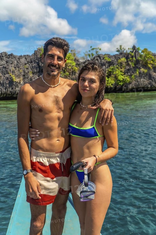 Young couple standing on boat with snorkeling gear, enjoying breathtaking view of turquoise water and rocky islands in coron, philippines