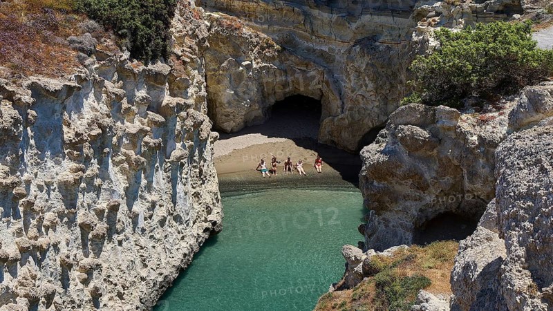 People swim through clear water between steep rock walls and a cave, volcanic island, island, Milos, Cyclades, Greek islands, Greece